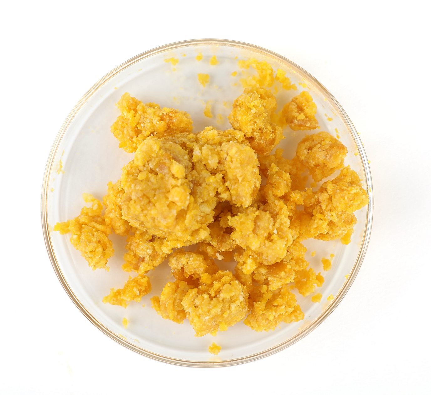 A pile of waxy, clumpy, yellow-colored hemp floral wax shown in a petri dish